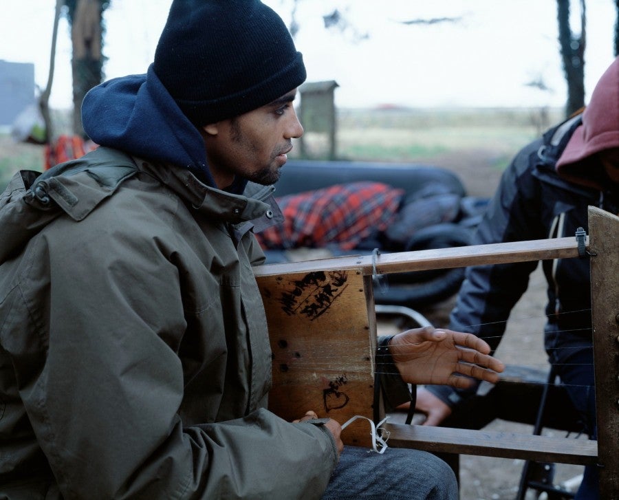 Bruno Serralongue, Jeune homme érythréen jouant de la musique, bois Chico Mendes, zone Marcel Doret, Calais, 8 février 2018. From the 'Calais' series, 2006-20. © Air de Paris, Romainville